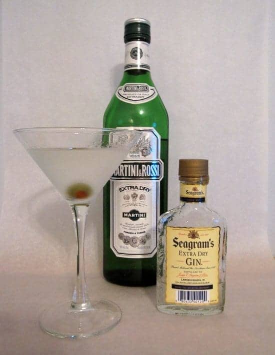 Martini ingredients with a bottle of vermouth, gin and a chilled and poured martini in a glass. 