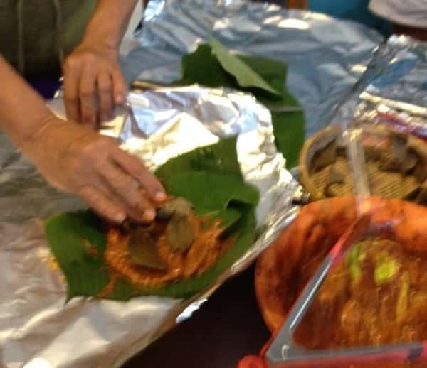 Folding the chicken in banana leaves.
