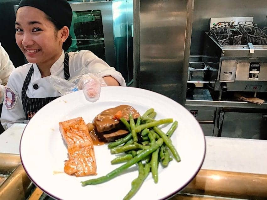 Waitress in the Lido buffet displays a salmon dinner.