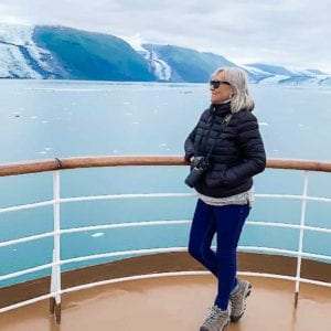Sherry stands near the railing of a cruise ship on Alaska cruise.