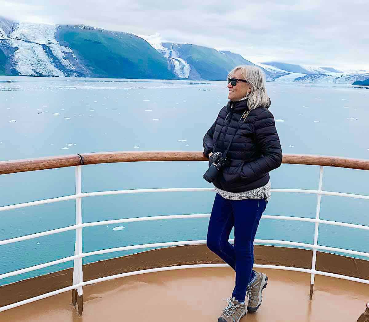 Sherry stands near the railing of a cruise ship on Alaska cruise. 