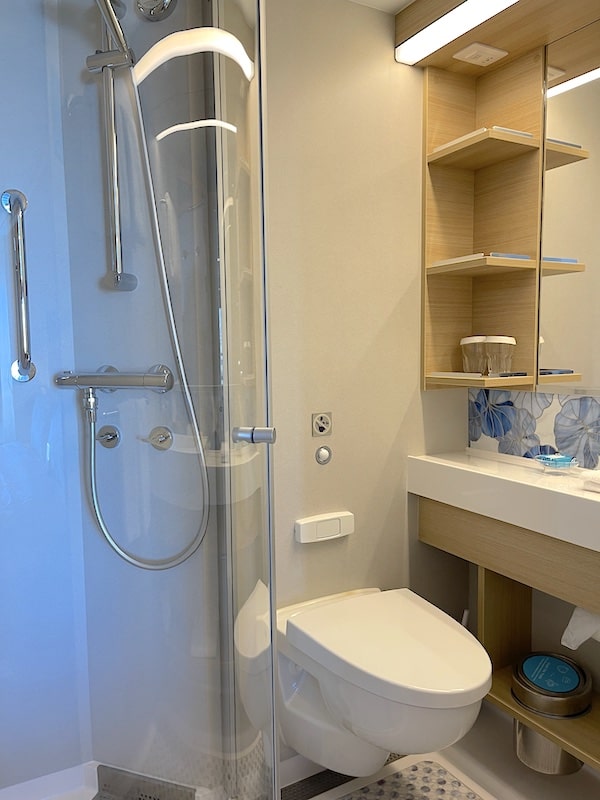 Wonder of the Seas stateroom bathroom with shower and sink area.